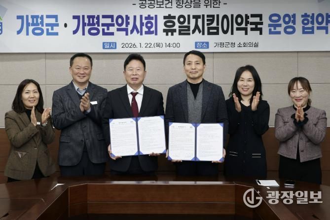 서태원 가평군수(사진 왼쪽에서 세번째)와 안병현 가평군약사회 회장(〃 네번째) 등이 22일 휴일지킴이약국 운영 협약식 후 협약서를 보이며 기념촬영을 하고 있다.